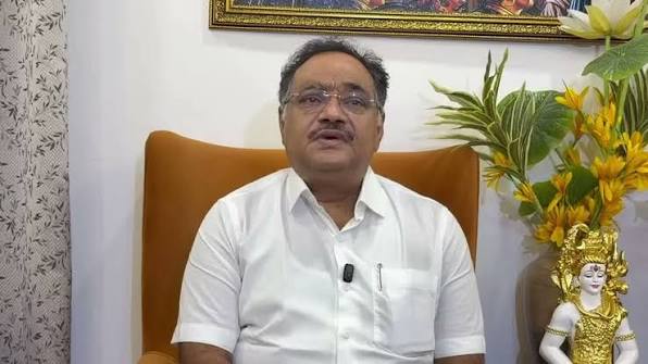 Samik Bhattacharya seated in an armchair, speaking to camera in a domestic interior