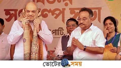 Samik Bhattacharya applauding on a public stage beside Union Home Minister Amit Shah at a party event