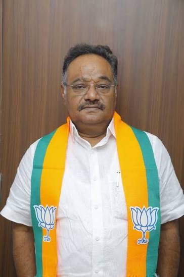Samik Bhattacharya standing in a white shirt wearing a party scarf, photographed indoors
