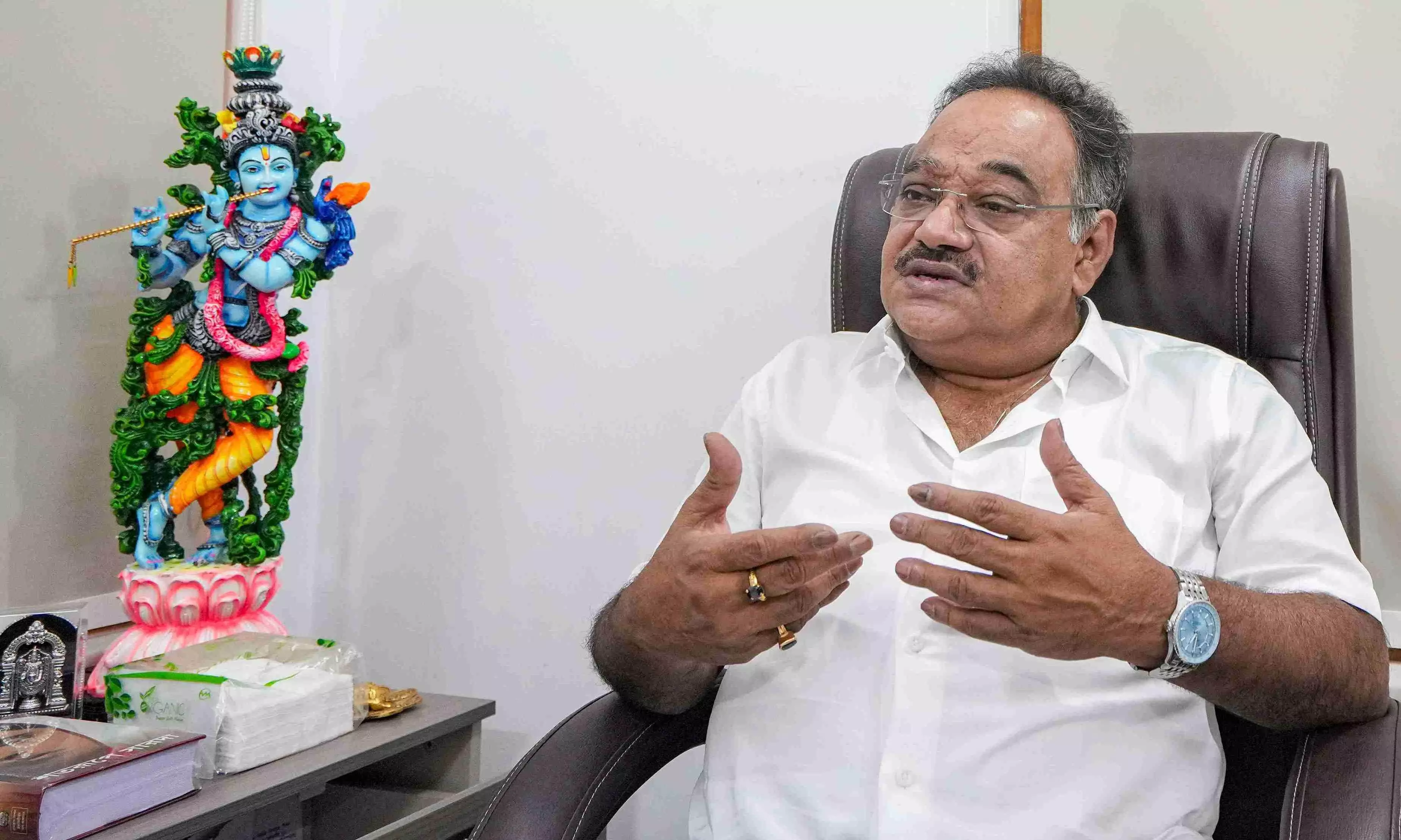 Samik Bhattacharya seated at his office desk in a white shirt, gesturing with both hands during an interview