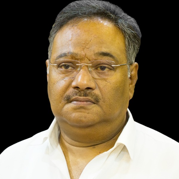 Studio portrait of Samik Bhattacharya in a white shirt, facing the camera against a black background