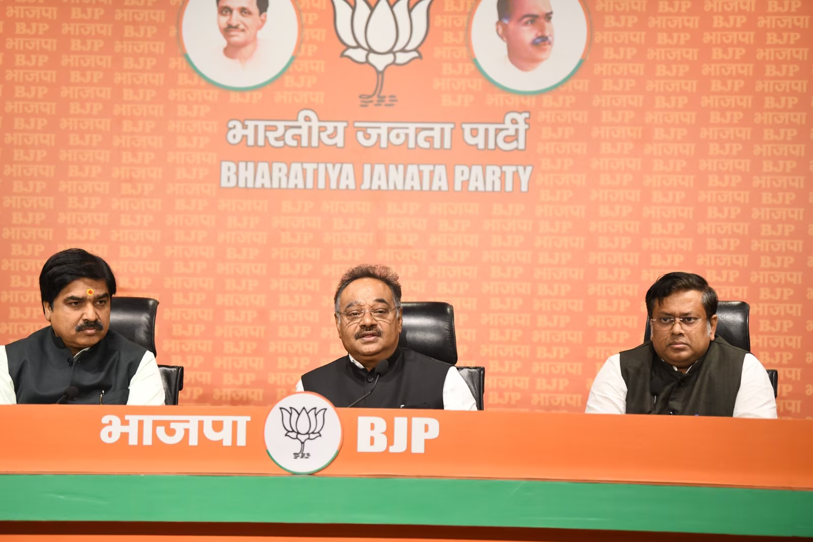 Samik Bhattacharya speaking at a Bharatiya Janata Party press conference, seated at a party dais with two colleagues